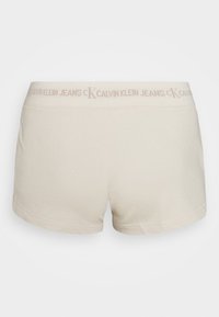 Světle béžové bavlněné šortky s elastickým pasem, na kterém je logo "CALVIN KLEIN JEANS", jednoduchý design a prošívané lemy.