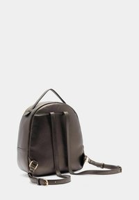 Dunkelbrauner Leder-Rucksack mit runder Form, ausgestattet mit einem Handgriff und verstellbaren Trägern, vor einem schlichten weißen Hintergrund.