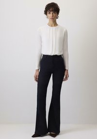 Witte blouse met lange mouwen en een geraffineerde halslijn, gecombineerd met hoge zwarte flared trousers. Glad stof met een getailleerde pasvorm.