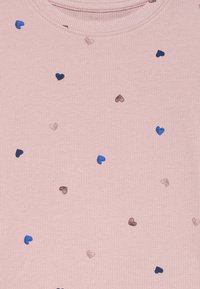 Tessuto a coste di un delicato rosa con piccoli cuori ricamati sparsi in tonalità di blu, marrone e malva.