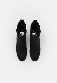 Botines negros de ante con un diseño elegante, cierre lateral de cremallera y punta redondeada, que cuentan con una plantilla acolchada para mayor comodidad.