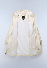 Giacca leggera beige con cappuccio, dotata di una fodera in rete, coulisse regolabile e tasche con zip. Textura esterna liscia.