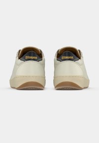 Μπεζ δερμάτινα αθλητικά παπούτσια με υφή σόλας από καφέ καουτσούκ, στρογγυλεμένο σχήμα και αντίθετες μαύρες λεπτομέρειες στη φτέρνα. Λογότυπο "Blauer" σε χρυσό στη φτέρνα.