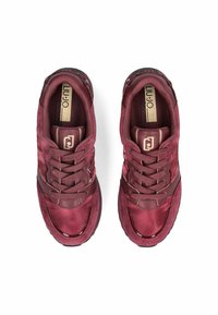 Une paire de baskets Bordeaux à lacets avec des cols rembourrés et des semelles texturées, vue de dessus sur un fond blanc.