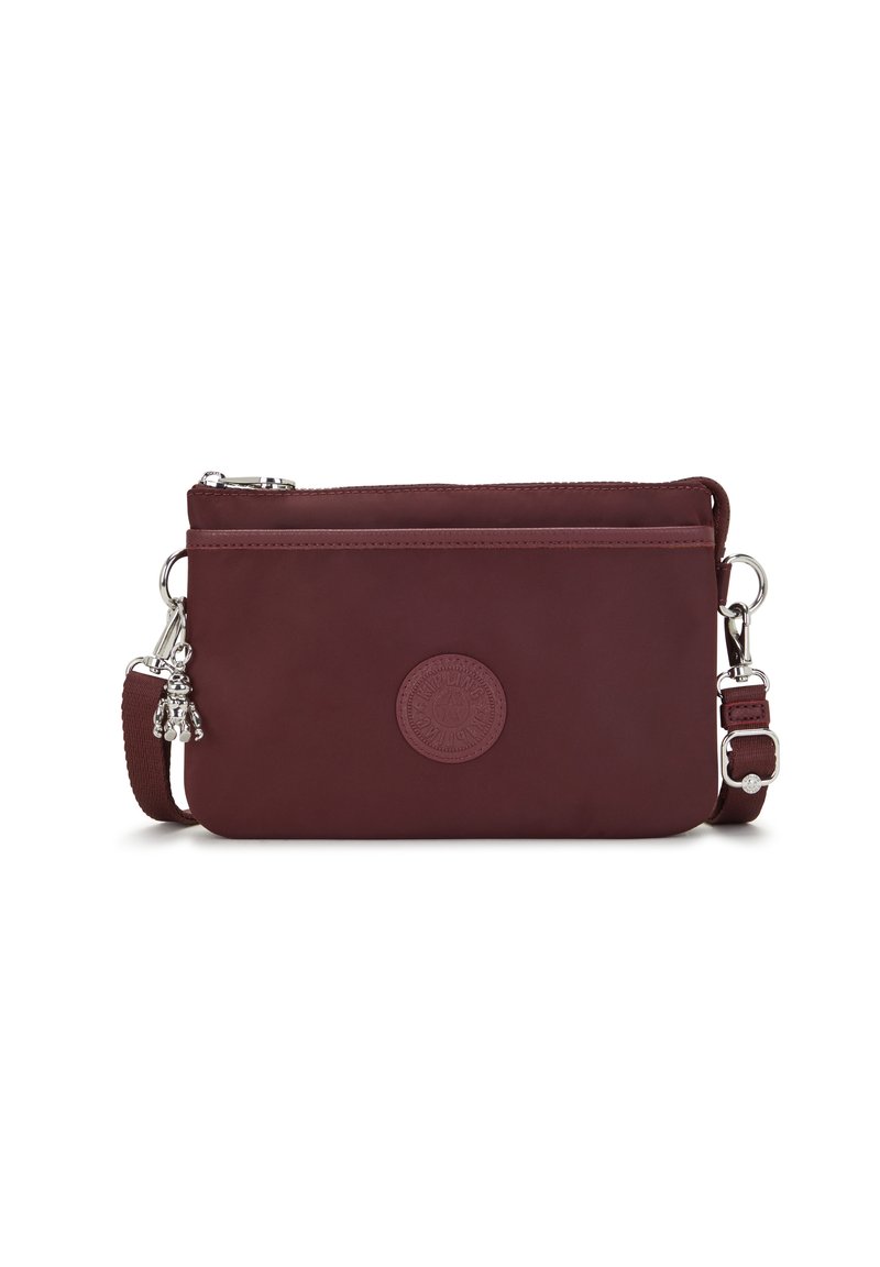 Bolso cruzado de cuero burdeos con correa ajustable, cierre de cremallera y logo en relieve, que presenta un charm decorativo y una textura suave.