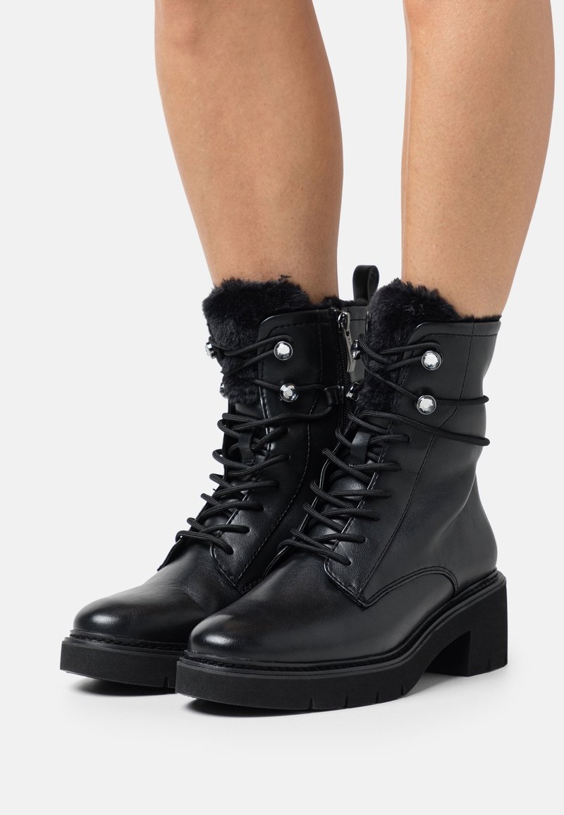 Bottes noires en cuir aux chevilles avec bordure en fausse fourrure, design à lacets, talon bloc et boutons argentés décoratifs. Texture lisse, construction robuste.