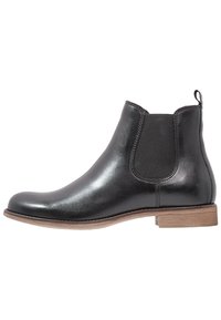 Schwarzer Chelsea-Stiefel aus Leder mit elastischen Seitenteilen, abgerundeter Zehenpartie, gesteppten Details und einem leichten braunen Holzabsatz.