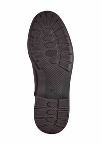 Suela de zapato de goma negra con superficie texturizada y patrones de tracción distintivos, que presenta elementos de tracción ovalados y circulares para un mejor agarre.