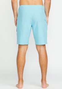 Shorts de bain bleu clair en matériau à séchage rapide, dotés d'une poche arrière et d'une taille plate. Texture lisse et design à longueur de genou.