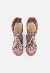 Gli stivali di gomma floreali rosa presentano un morbido rivestimento bianco, una chiusura con lacci e dettagli metallici, e una superficie testurizzata con motivi intricati.