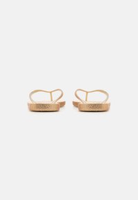 Guld platta sandaler med tunna remmar, en strukturerad ovandel och en minimalistisk design. Sulan är platt med en subtil skimrande finish.