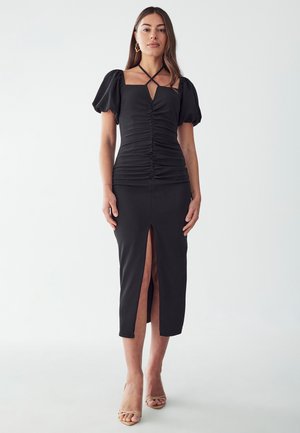Black dress with puff sleeves, fitted bodice, gathered texture, and a front slit; crafted from stretchy fabric for comfort and fit.
