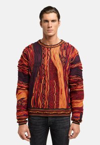 Mehrfarbiger gestrickter Pullover mit komplizierten Mustern in Rot, Orange und Schwarz. Strukturiert mit Ärmeln und Saum sowie gerippten Akzenten.