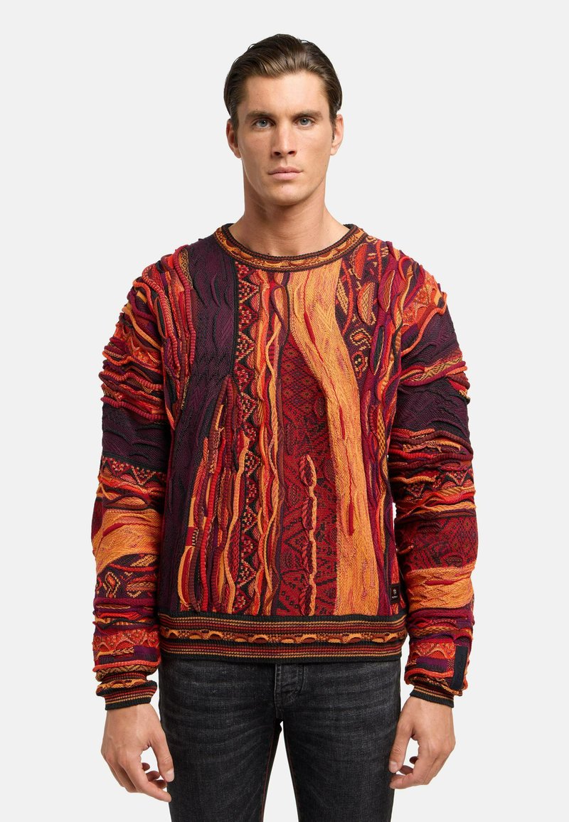 Mehrfarbiger gestrickter Pullover mit komplizierten Mustern in Rot, Orange und Schwarz. Strukturiert mit Ärmeln und Saum sowie gerippten Akzenten.