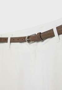 Ceinture en daim marron avec boucle argentée passée dans les passants blancs du pantalon.
