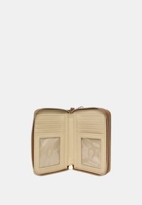 Cartera de cuero crema con cierre de cremallera. El interior cuenta con ranuras para tarjetas y dos ventanas transparentes para identificación. Textura suave, diseño minimalista.