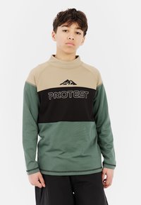 Langekous, kleur geblokte top in beige, zwart en groen. Heeft een hoge kraag, logo grafiek en contrasterende stiksels. Glad textuur.