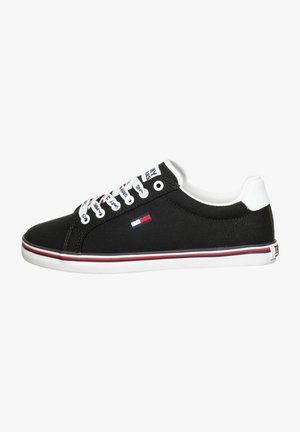 Czarny niski sneaker z białą podeszwą, białym i czerwonym paskiem, białymi sznurowadłami z tekstem oraz małym logo flagi w kolorach czerwonym, białym i niebieskim na boku.