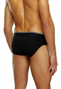 Schwarze Baumwoll-Slips mit enganliegendem Schnitt, einem weißen gestreiften Bund und glatter Textur, betrachtet von hinten.