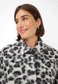 Leopardprint wollen jas met een kraag, vier zwarte knopen en een zachte textuur, met zwarte vlekken op een lichtgrijze achtergrond.