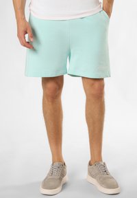 Mintgroene katoenmix shorts met zijzakken, een elastische tailleband en geborduurd logo-detail. Gecombineerd met lichtgrijze suède sneakers.