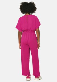 Fuchsia jumpsuit with short sleeves, elastic waist, and a back keyhole. Made from textured fabric, featuring loose, wide legs and casual styling.
