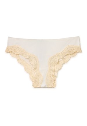 Beżowa bielizna damska z kwiatową koronką przy otworach na nogi na białym tle.