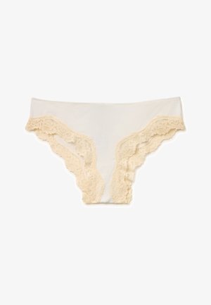 Sous-vêtements féminins couleur crème avec bordure en dentelle florale le long des ouvertures des jambes sur un fond blanc.