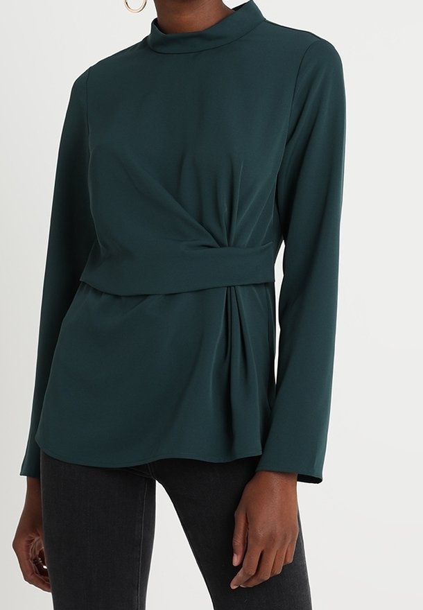Tyrkysově zelený top s dlouhými rukávy, vysokým výstřihem a zkrouceným předním designem. Hladká, lehká látka s volně splývajícím lemem a záhybovým detailem.