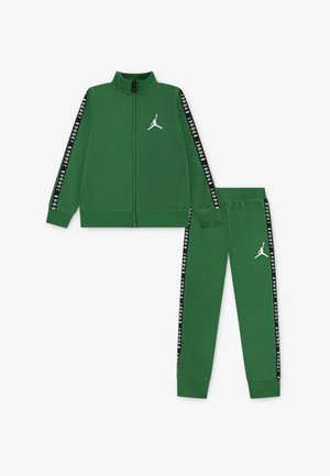 Tuta verde con giacca a zip e pantaloni. Presenta un logo bianco e strisce laterali nere con testo. Materiale liscio, design aderente.