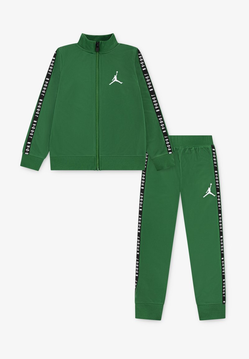 Chándal verde con chaqueta con cremallera y pantalones. Presenta un logo blanco y rayas laterales negras con texto. Material suave, diseño ajustado.
