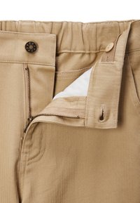 Le pantalon kaki présente un motif en chevron avec une fermeture éclair, un bouton et une taille élastique pour un ajustement confortable.