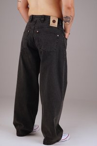 Black loose-fitting jeans with a textured fabric. Features a tan label on the back waistband and copper-tone rivets.