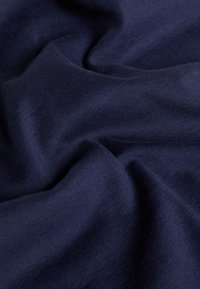 Mörkblått tyg med en mjuk, slät textur och subtil lyster, med mjuka veck och rynkor genom hela ytan.