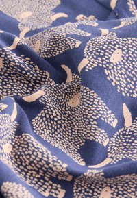 Marineblåt stof med et cremefarvet mønster af pindsvin med teksturerede detaljer, blødt udseende og en let krøllet overflade.