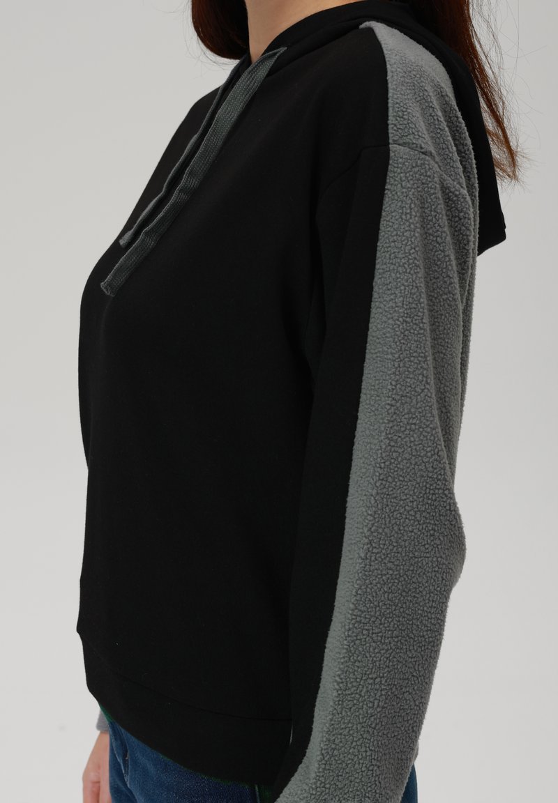 Czarna bluza z kapturem z szarymi panelami z frotte na rękawach, teksturowana tkanina, sznurek przy kapturze oraz luźny krój.