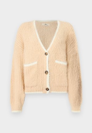 Cardigan doux et moelleux de couleur pêche claire avec un col en V et des bordures blanches. Il présente trois boutons, deux poches avant et des poignets côtelés.