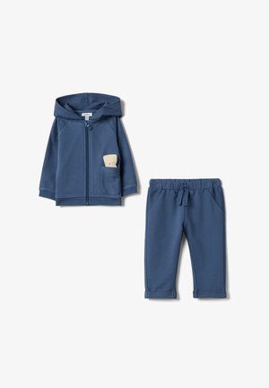 Tweedelige peuteroutfit van zachte blauwe stof. Hoodie met ritssluiting en zak waarin een pluchen beer zit. Bijpassende broek met elastische tailleband.