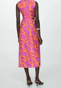 Robe sans manches, longueur genou, en tissu imprimé floral violet et orange. Présente une silhouette ajustée avec un détail découpé à la taille.