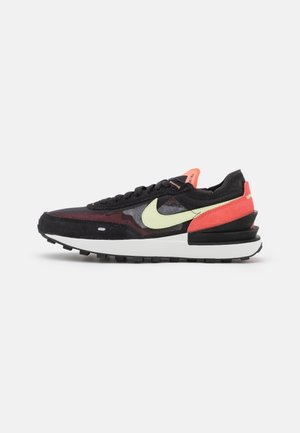 Black and red suede sneaker with mesh upper, featuring a neon green Nike swoosh, pink accents, and a thick white midsole. Textured rubber outsole.