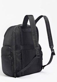 Zaino nero con una superficie texturizzata, numerose tasche con zip, spallacci imbottiti e una maniglia rinforzata. Presenta un design elegante e compatto.