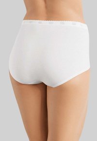 Slip in cotone bianco con vita scallopata, caratterizzato da una texture liscia e senza motivi visibili. Design senza cuciture sul retro.