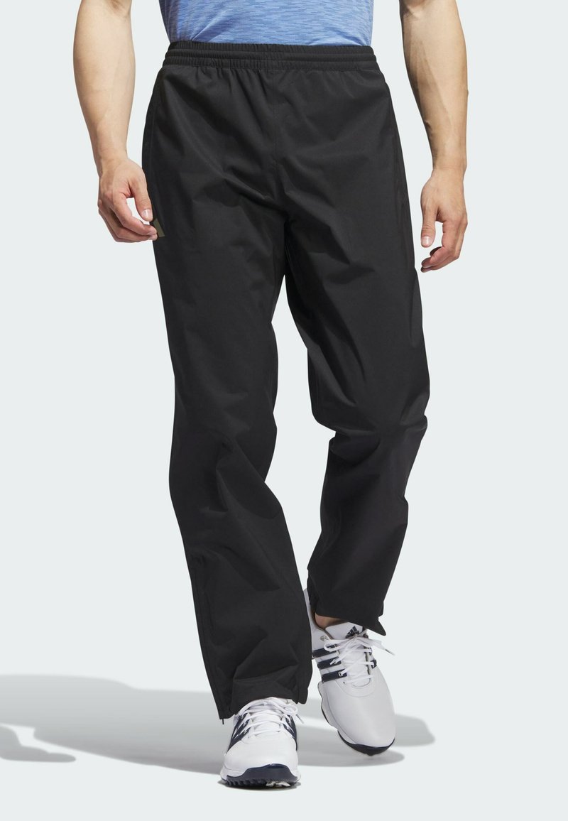 Pantalons noirs, légers et imperméables avec une taille élastique et une coupe décontractée, dotés de poches latérales et d'une texture lisse.