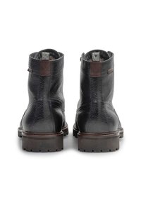 Botas de tobillo de cuero negro con superficie texturizada, acentos marrones en contraste, suelas de goma resistentes y lengüetas en el tobillo para facilitar su uso.