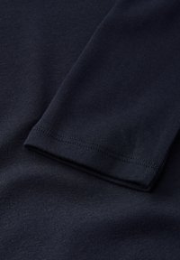 Navyblauw katoenen stof met een gladde, licht rekbare textuur en taps toelopende mouwmanchetten die schone stiksels en een minimalistisch ontwerp tonen.