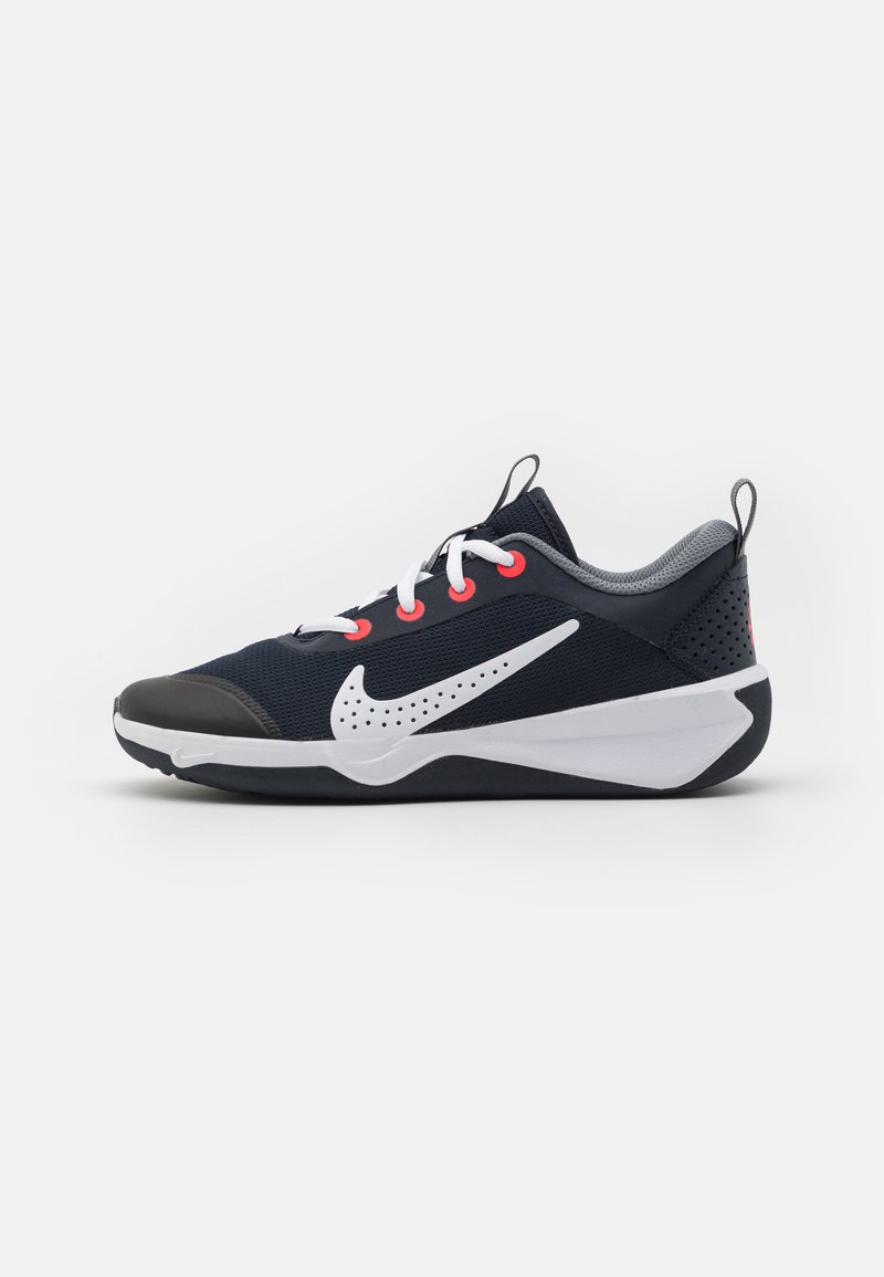 Jūras spēku sporta apavi ar acs augšdaļu, balto swoosh, kontrastējošām sarkano akcentiem un pelēkiem elementiem; aprīkoti ar mīkstu apkakli un teksturētu zoli.