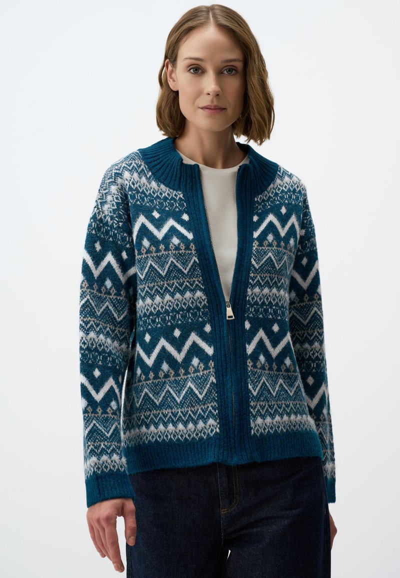 Cardigan tricoté avec un motif géométrique bleu et blanc, fermeture éclair sur toute la longueur et col côtelé. Matière en mélange de laine.