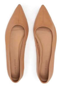 Spitze Ballerinas aus hellbraunem Leder mit glatter Textur. Das Innenfutter besteht aus einem weichen Material, das auf der Innensohle mit "KAZAR STUDIO" gekennzeichnet ist.