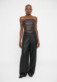 Donkerbruin leren strapless top gecombineerd met losse zwarte leren wijde broek, met een gladde textuur en een minimalistisch ontwerp.