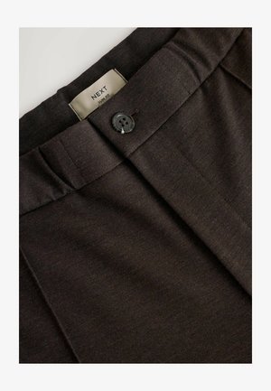 Tumed pruunid kohandatud püksid, millel on ühe nööbi sulgemine, pleatide esiosa ja silt "NEXT Slim Fit". Kanga tekstuur on sile.